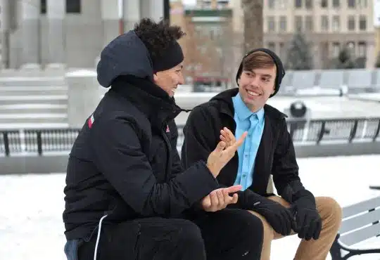 two men talking while sitting on bench